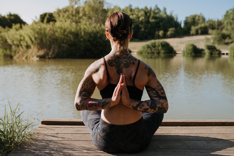 Woman performing a graceful yoga pose on a wooden pier by a serene lake.